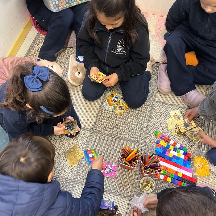 Estudiantes jugando con naipes y material concreto sentados en el suelo